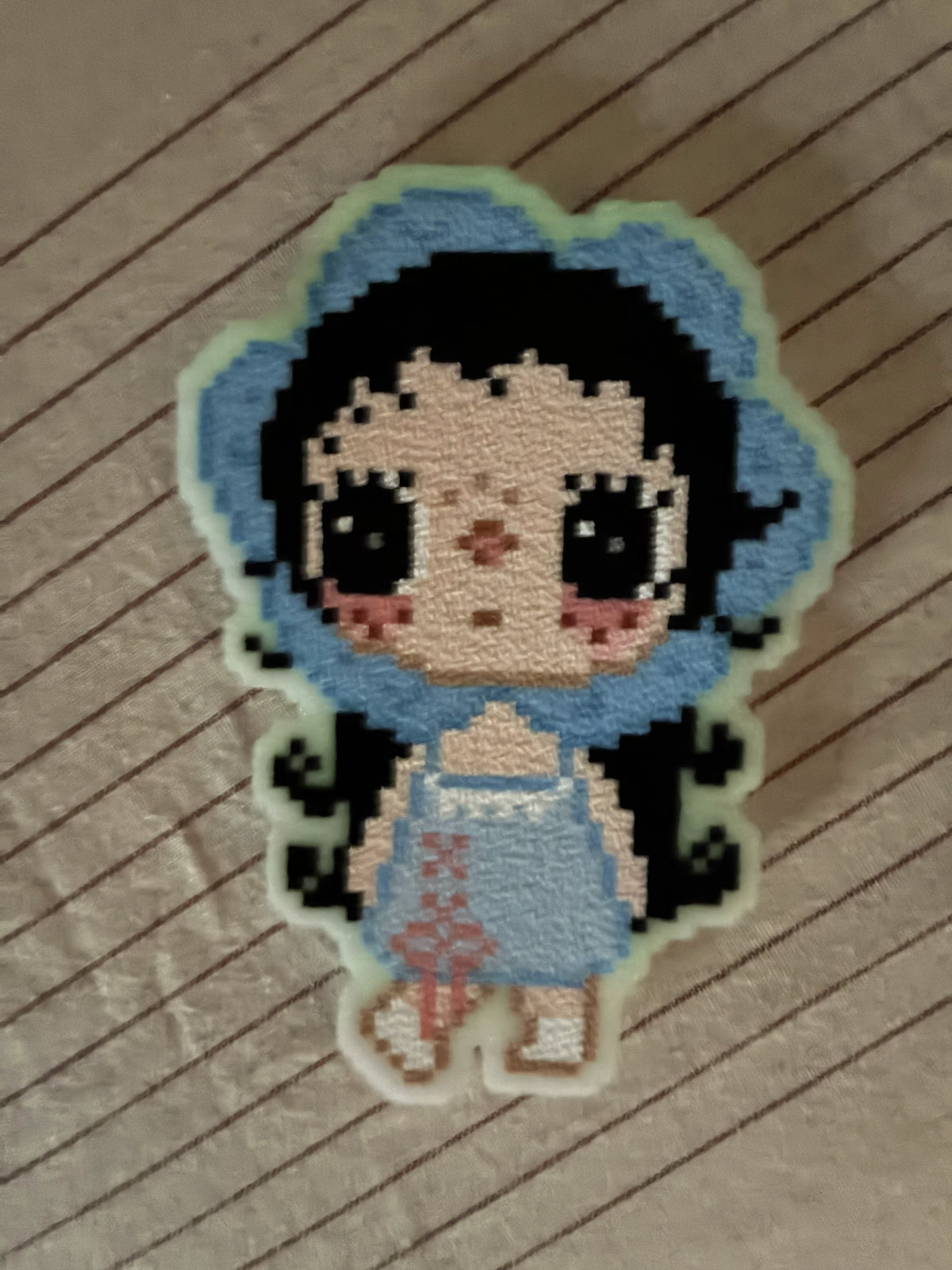 Personnage en perles à repasser entouré d'un contour en perles phosphorescentes, dans la pénombre