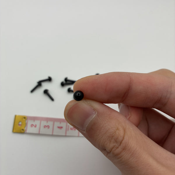 Œil noir demi-boule 4 mm tenu entre les doigts pour montrer la taille