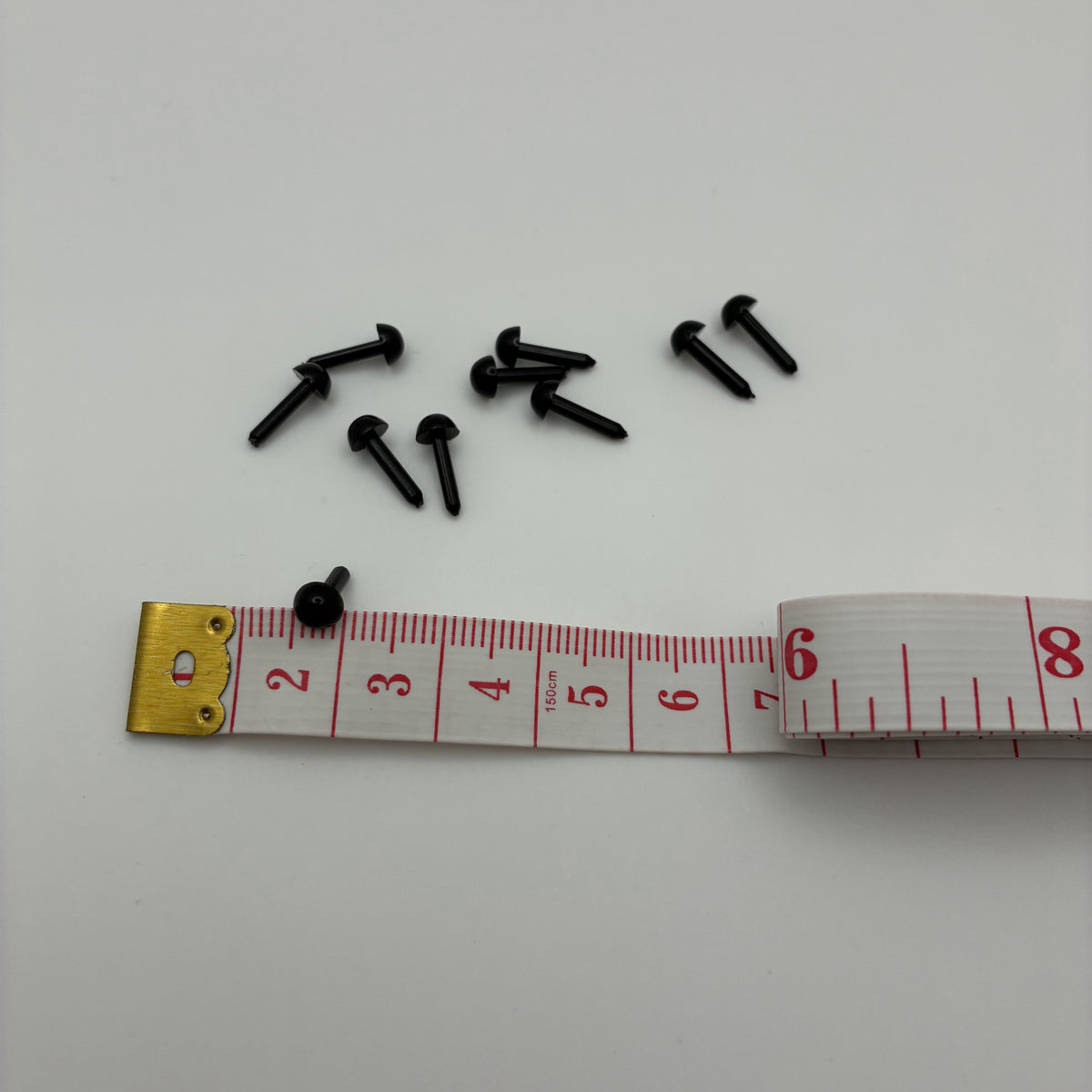 Yeux noirs demi-boule à tige 3 mm pour feutrage à l'aiguille, à côté d'un mètre ruban