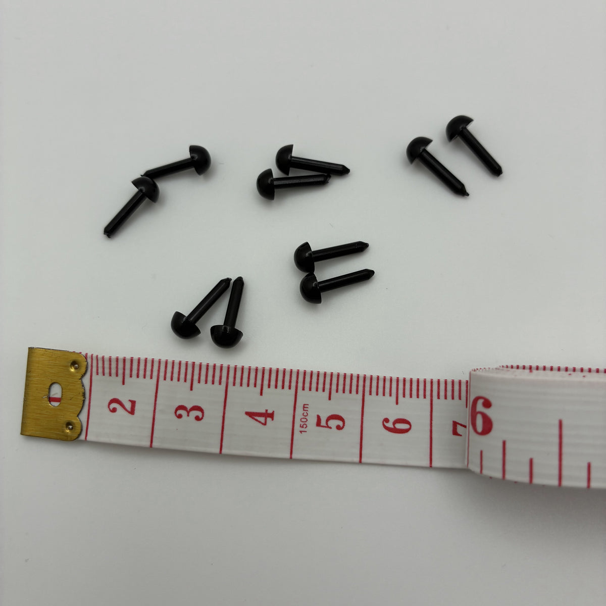 Yeux noirs demi-boule à tige 4 mm pour feutrage à l'aiguille, à côté d'un mètre ruban